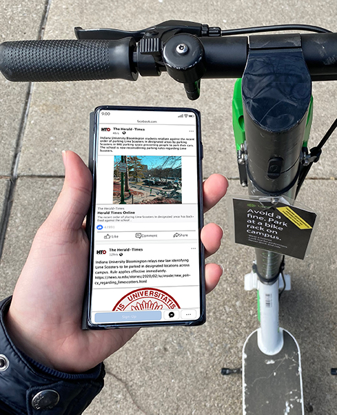 A phone showing a news app, held over a scooter