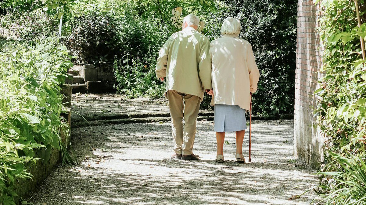 An older couple walking along a garden path